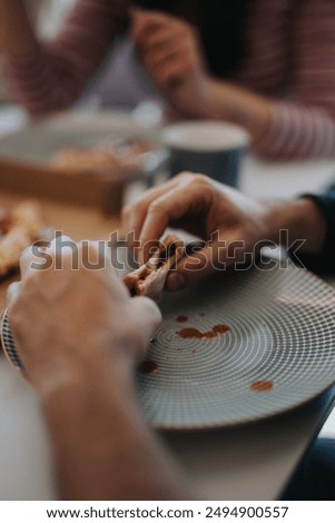A close-up image capturing the essence of dining together, with a focus on hands and a half-eaten sandwich, highlighting casual eating.