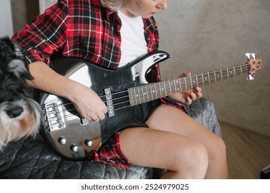 Close-up image capturing the hands of a woman in a checkered shirt playing a bass guitar, showcasing musical skill and casual style - Powered by Shutterstock