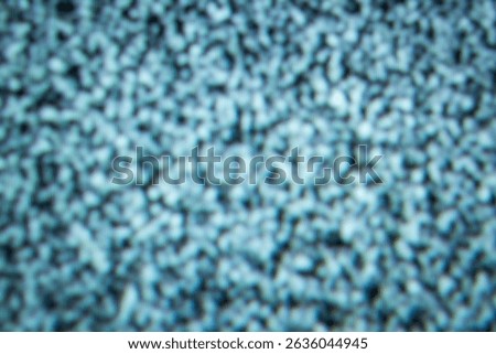 A close-up image capturing static noise present on a television screen. The image highlights a random pattern of black and white dots, creating an abstract visual effect.