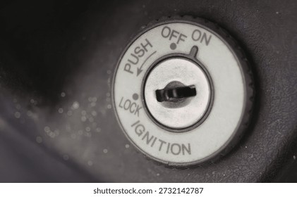 A close-up image of a car ignition switch in the off position, showing the keyhole and surrounding labels.