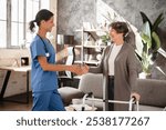 Closeup image of caregiver nurse caretaker doctor greeting giving handshake to senior old elderly grandmother patient female with walking frame with motion immobility in hospice at home. Homecare