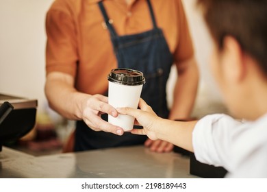 Closeup image of coffeeshop barista giving cup of coffee to customer