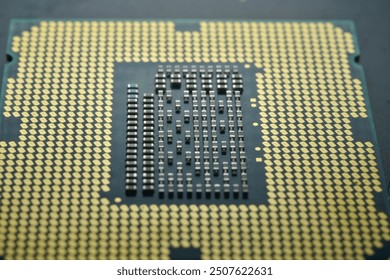 A close-up image of a computer CPU  IT hardware, focusing on the detailed array of gold-colored contact pins and the intricate grid pattern on the processor’s surface.