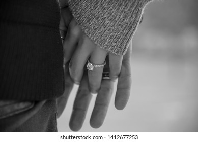 Close-up image of a couple holding hands and her engagement ring in black-and-white