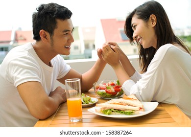 Close-up image of a couple in-love having weekend breakfast on the balcony in the apartment