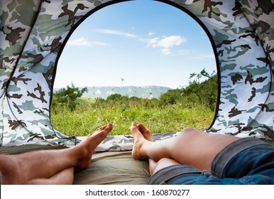 Closeup image couple legs lying together in tourist tent 