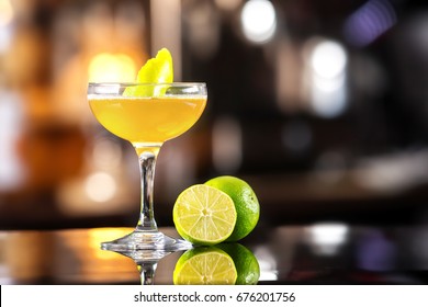 Closeup image of daiquiri cocktail decorated with lemon at bar counter background.