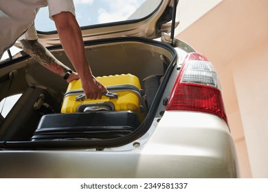 Closeup image of driver taking suitcase out of car truck after arriving to hotel