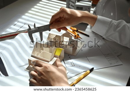 Close-up image of Engineer or architect man using vernier caliper to measure architectural model, check house model scale.