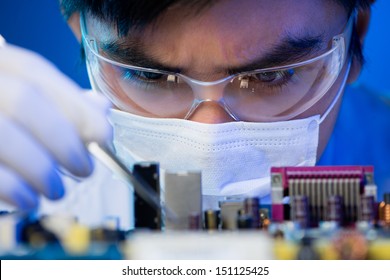 Close-up Image Of An Engineer Concentrated On Electronic Assembling On The Foreground