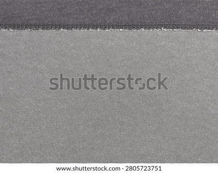 Close-up image of fabric texture showing detailed weave and stitching with gray and purple threads.
