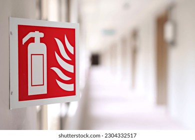 Close  up image features an emergency sign fire extinguisher in building corridor  The image has selective focus  drawing attention to the fire extinguisher sign 