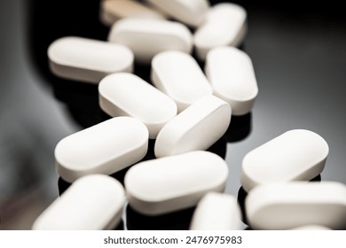 Close-up image featuring a row of white, oval-shaped pills scattered on a dark, reflective surface. These may represent opioids, highlighting issues related to medical use and overdose risks.