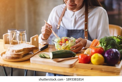 Closeup image of a female chef cooking fresh mixed vegetables salad in kitchen