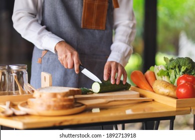 Closeup Image Of A Female Chef Cutting And Chopping Vegetables By Knife On Wooden Board In Kitchen