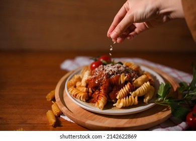 Close-up Image, Female Chef Hands Sprinkling Fusilli Pasta With Parmesan Cheese. Italian Pasta Restaurant And Cooking Concept.