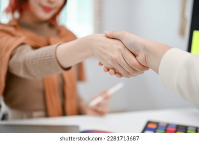 Close-up image of a female graphic designer shaking hands with her client in the office. - Powered by Shutterstock