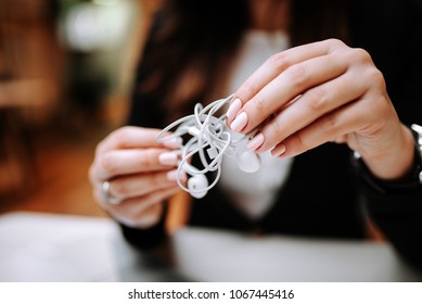 Close-up Image Of Female Hands Holding Tangled Earphones.