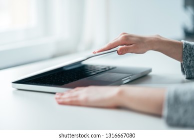 Close-up image of female hands open or close laptop on white table.