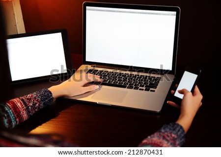 Closeup image of a female hands using smartphone and laptop