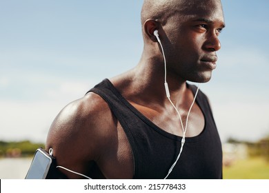 Close-up image of fit young man wearing earphones focusing for his run. African male model wearing earphones to listen music. - Powered by Shutterstock