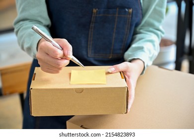 Close-up Image, Focus Hands, Female Writing A Customer Name And Address On A Small Parcel Box. Online Shopping And Shipping