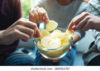 Closeup Image Of Friends Sharing And Eating Potato Chips At Home Party Together