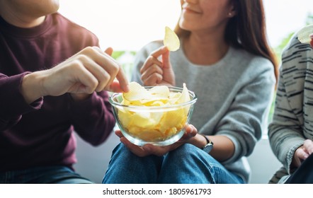 Closeup Image Of Friends Sharing And Eating Potato Chips At Home Party Together