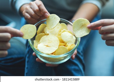 Closeup Image Of Friends Sharing And Eating Potato Chips At Home Party Together