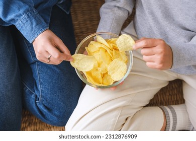 Closeup image of friends sharing and eating potato chips together