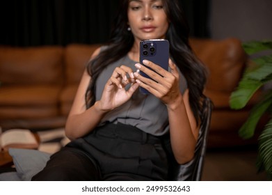 A close-up image of a gorgeous Asian businesswoman using her smartphone while sitting on a chair in a room, reading text messages or chatting. people and wireless technology concepts - Powered by Shutterstock