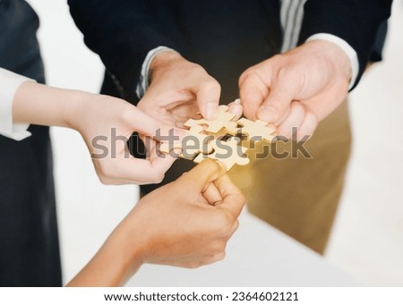 Closeup image of a group of people holding and putting a piece of white jigsaw puzzle together,A business group wishing to bring together the puzzle pieces