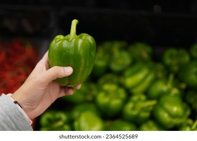 Closeup image of hand holding green capsicum or green bell pepper in supermarket. - Powered by Shutterstock