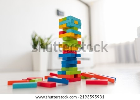 Closeup image of a hand holding and playing Jenga or Tumble tower wooden block game
