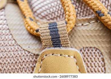 Close-up image of a handle and strap area of outdoor gear or luggage, with textured fabric, stitching details, and a blurred background suggesting a collection of outdoortravel items