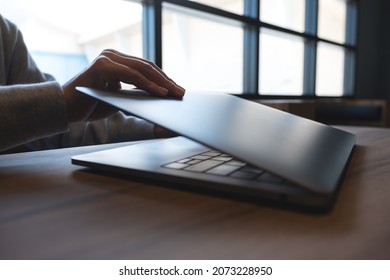 Closeup image of hands close and open a laptop computer on table after finished using it