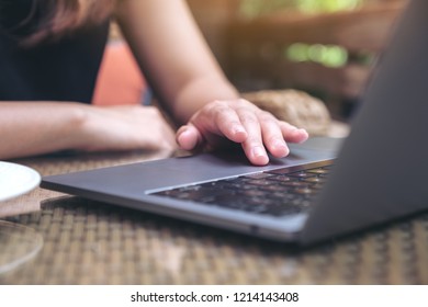 Closeup image of hands using and touching on laptop touchpad on wooden table