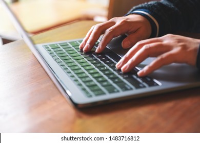 Closeup image of hands using and typing on laptop computer keyboard on the table