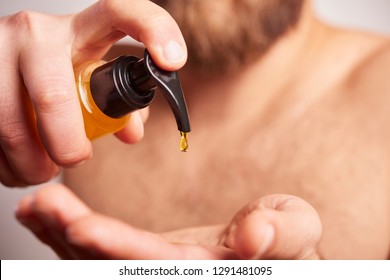 Close-up image of handsome man holding locion or oil for beard