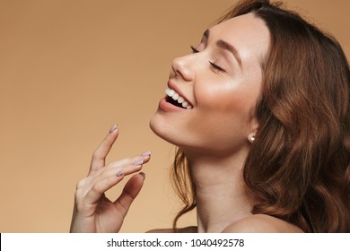 Closeup Image Of Happy Beautiful Woman 20s With Long Auburn Hair Posing On Camera In Profile With Magnificent Smile Isolated Over Beige Background