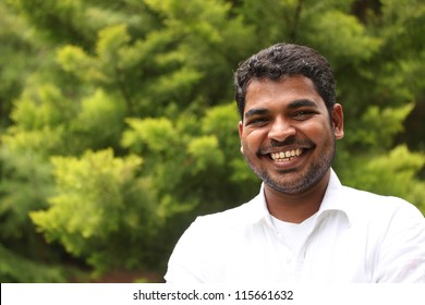 Close-up image of happy, excited & handsome asian/indian man with smile. The person is wearing a white shirt & the picture is shot in natural settings - Powered by Shutterstock