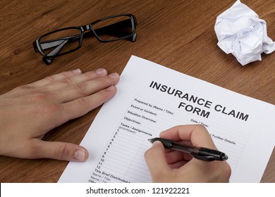 Close-up Image Of A Human Hand About To Fill Up The Blank Insurance Claim Form