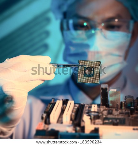 Close-up image of an it-engineer with chip holding in tweezers on the foreground 