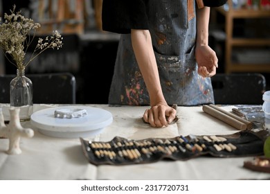 Close-up image of a male artist potter kneading raw clay at his worktable in his pottery studio. handicraft, pottery workshop, earthenware, sculpture - Powered by Shutterstock