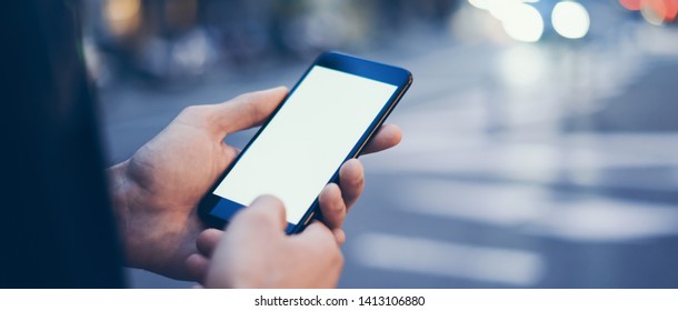 Closeup image of male hand holding modern smartphone with blank screen. Mockup ready for text message or content. Man's hands with cellphone. Empty display. Night street, bokeh light - Powered by Shutterstock