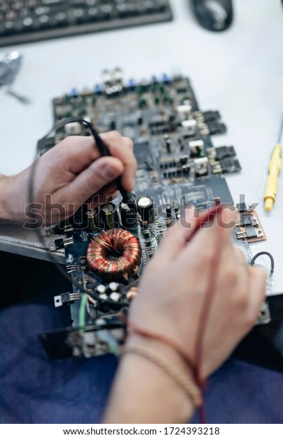 A close-up image of a male technician's hand-a
man measuring the electrical voltage of a car audio amplifier using
a digital multimeter. Concept of maintenance and repair of computer
equipment.