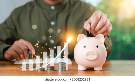 Close-up image of man hand putting coins in pink piggy bank for account save money. saving money wealth and financial concept, Business, investment, Financial planning. saving money for future plan. - Powered by Shutterstock