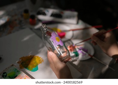 Close-up image of a man painting on a glass bottle, handcrafting home decoration, joining an art workshop. art workshop, creative activity, reuse - Powered by Shutterstock