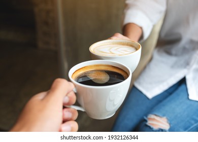 Closeup Image Of Man And Woman Clinking White Coffee Mugs In Cafe