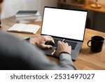 Close-up image of a man working on laptop computer at a table, typing on the laptop keyboard. the laptop with a white screen mockup